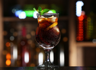 Glass of cocktail in bar on bright blurred background