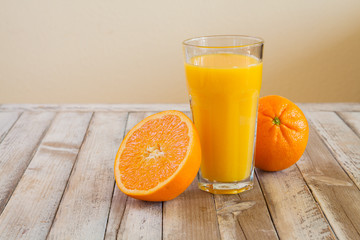 Orange fruit and glass of juice on white wooden background