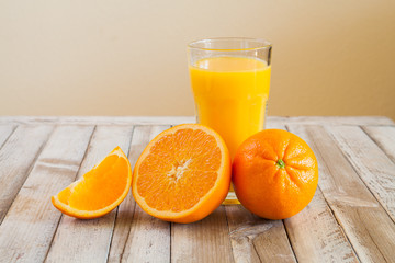 Orange fruit and glass of juice on white wooden background