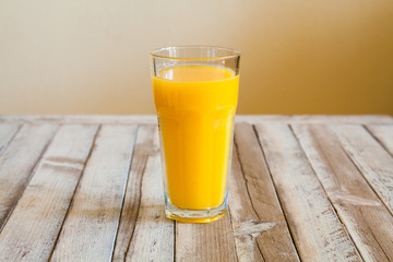 Glass of orange juice on white wooden background