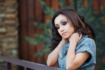 Beautiful woman in a gray knitted sweater leaned on the railing