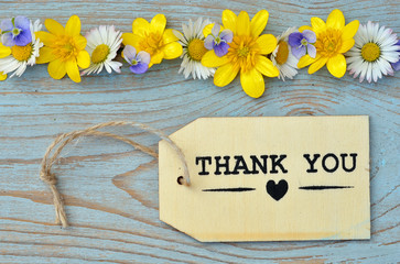 wooden background with thank you label and field flowers