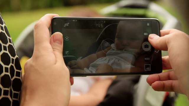 Mother Shoots Picture To Baby In Pushchair With Phone