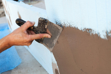 Man hand with trowel plastering a wall