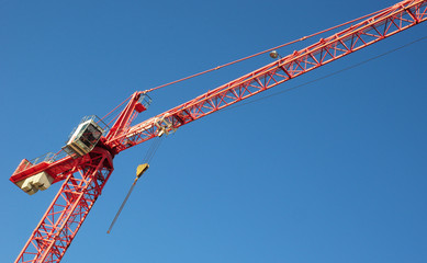 Red industrial construction crane above blue sky background