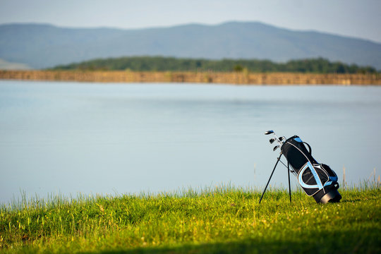 Bag with clubs on a green golf course.
