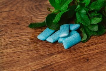 chewing gum and green mint on a wooden background