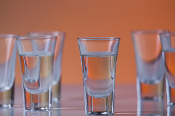 shot glass filled with vodka on a orange background