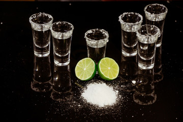 Tequila with lime on black background