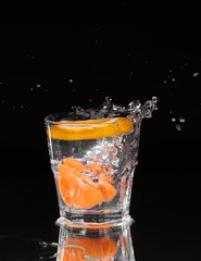 Slice of lemon splashing into a glass of water with