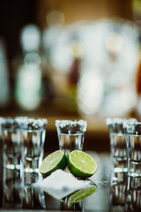 shots of tequila with lime and salt on a wooden table bar