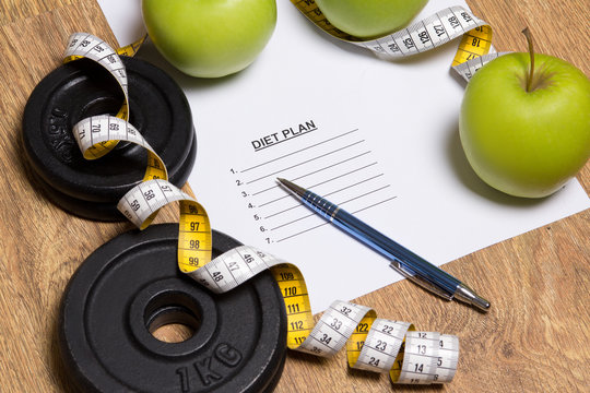 sheet of paper with diet plan, apples and dumbbell