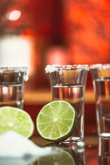 shots of tequila with lime and salt on a wooden table bar