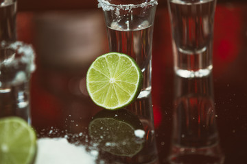 shots of tequila with lime and salt on a wooden table bar