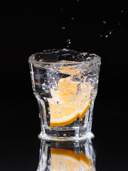 Slice of lemon splashing into a glass of water with