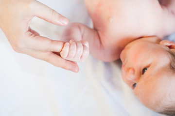 Baby girl holding her mother's finger