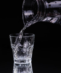 pouring water on a glass on black background
