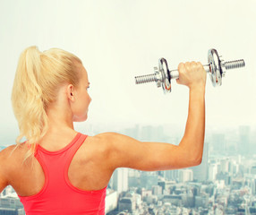 sporty woman with heavy steel dumbbell from back