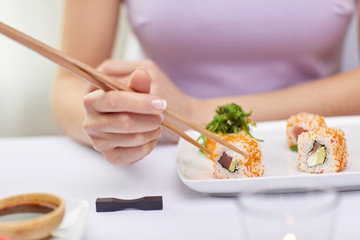 close up of woman eating sushi at restaurant
