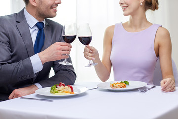happy couple with glasses of wine at restaurant
