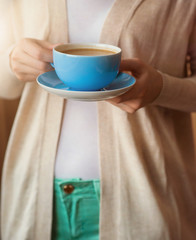 Unrecognizable woman holding a cup of coffee in her hands