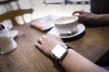Obraz na płótnie Canvas In coffee bar a woman using her smartwatch.