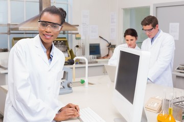 scientist smiling at camera while colleagues working together