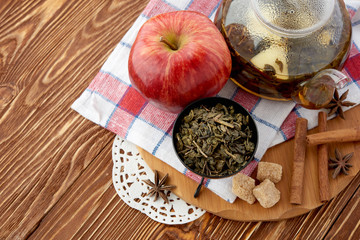 Ripe apple, cinnamon and fruit drink in glass teapot on wooden