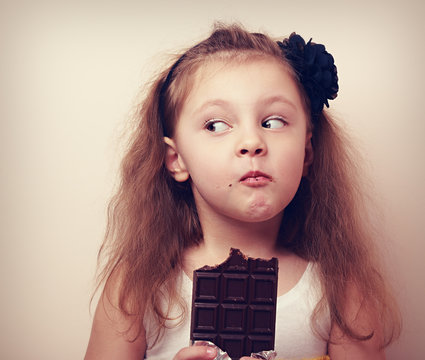 Thinking humor kid face eating chocolate. Closeup vintage