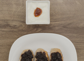 Jam on slices of bread and yogurt in white bowl