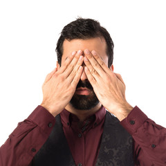 Man wearing waistcoat covering his eyes