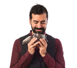 Man wearing waistcoat holding a jar glass with coffee inside