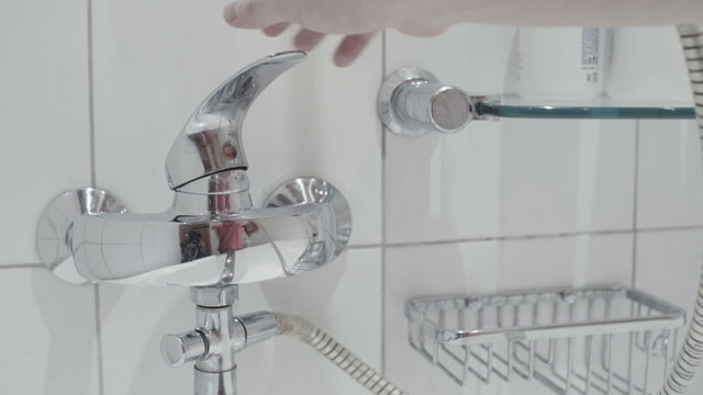 the man opens tap in white bathroom close up slow motion