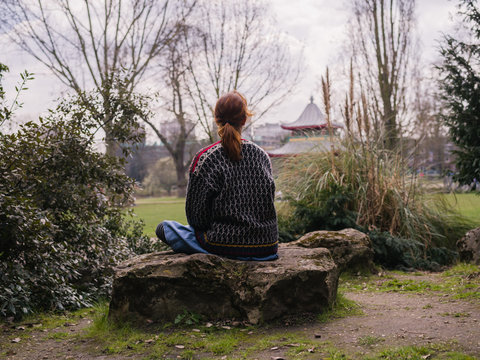 Young woman sitting on a rock in the park