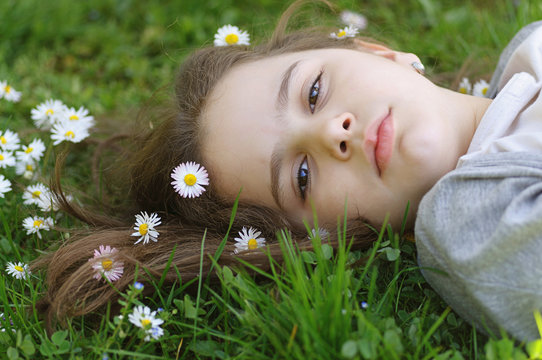 Girl lying in the grass surrounded with white flowers