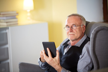 Senior man at home reading on a e-book 6