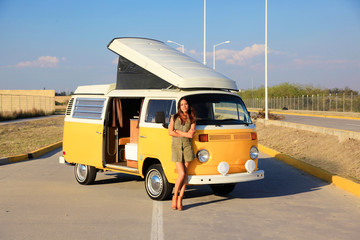 Beautiful woman standing in front of a yellow camper