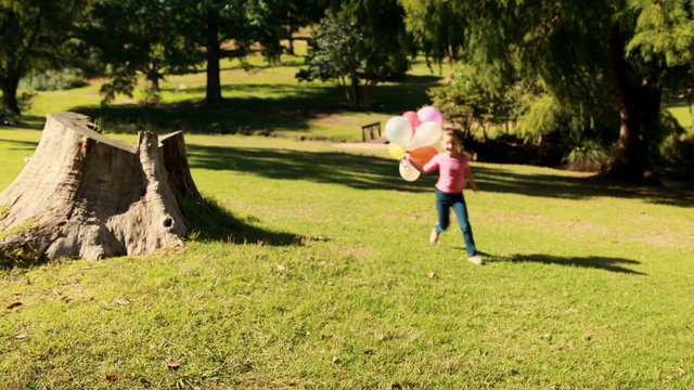 Happy little girl holding balloons
