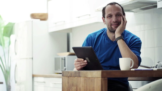 Portrait of happy man with tablet computer drinking coffee