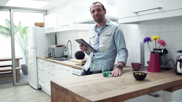 Portrait of happy man with tablet computer standing in kitchen
