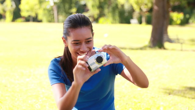 Smiling brunette taking pictures in the park