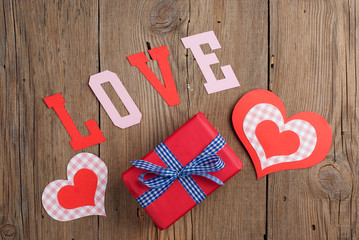 Gift and paper hearts on old wooden background