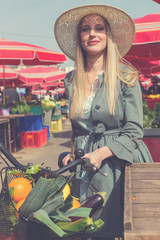 Attractive blonde woman with straw hat and bike at market.