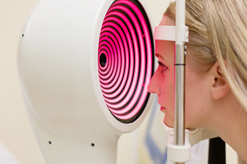 Young woman having her eyes examined by an eye handsome elderly