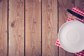 Wooden background with plate and silverware. View from above