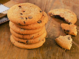 Stacked chocolate chip cookies on a wooden table.