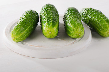 Fresh cucumbers on white cutting board.