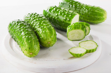 Fresh cucumbers on a white cutting board.