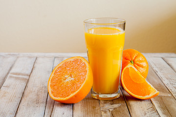 Orange fruit and glass of juice on white wooden background