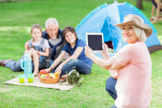Happy Grandmother Photographing Family At Campsite